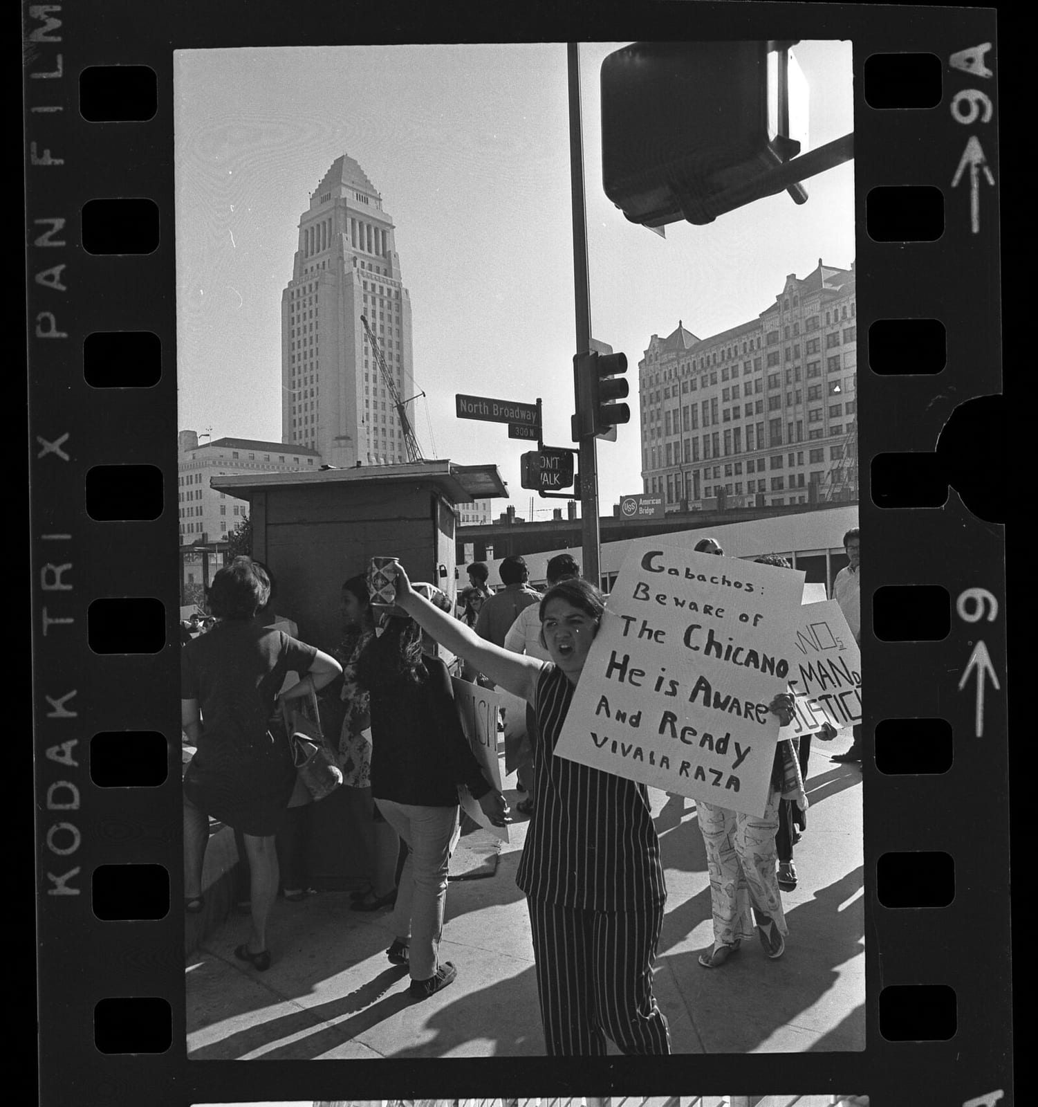 Demonstrator with sign stating "Gabachos:Beware of The Chicano He is Aware and Ready Viva La Raza" outside of Hall of Justice in Los Angeles, Calif., 1969, 1969, Los Angeles